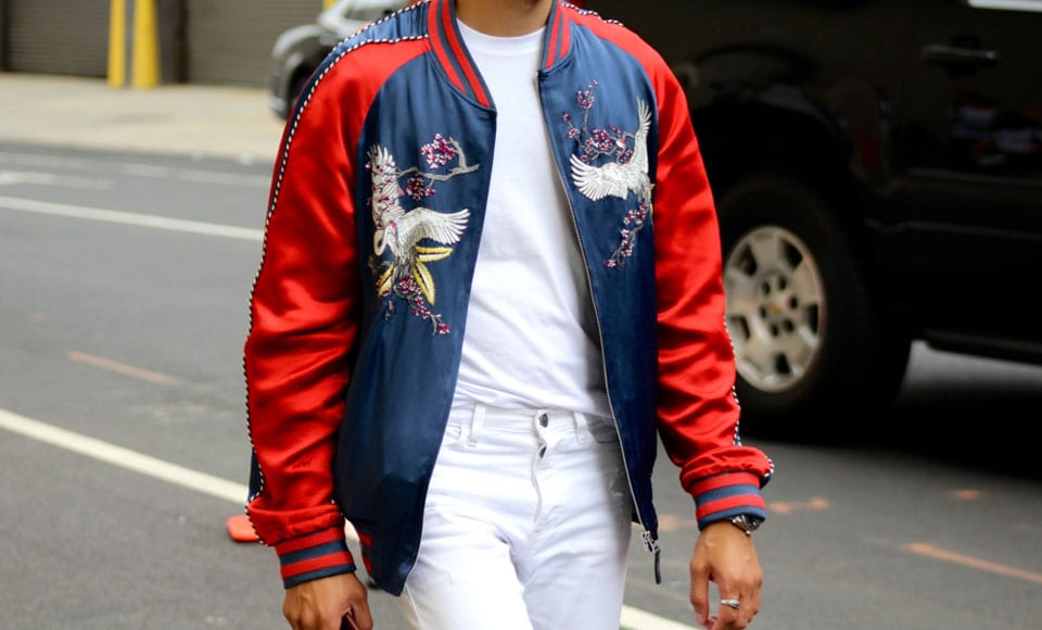 An expensive and brightly coloured bomber jacket styled with white jeans and a tee.