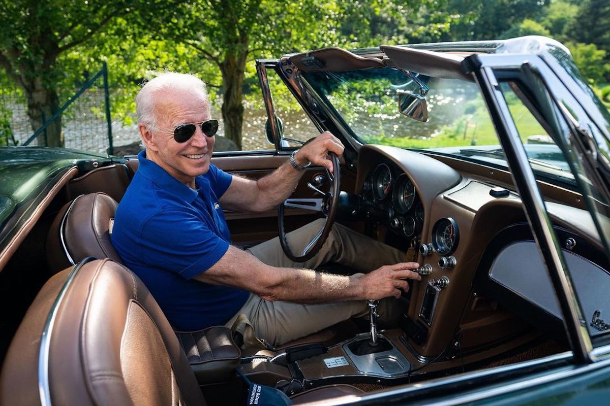 Joe Biden smiling to the camera behind the wheel of his Corvette.