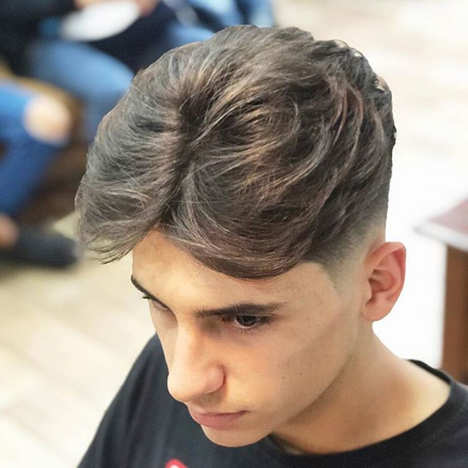 Young man with curtains hairstyle with faded sides.
