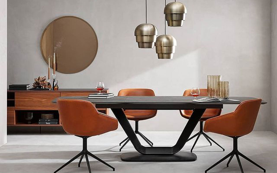 Black Bo Concept dining table with tan-leather chairs, gold pendant lighting and gold mirror