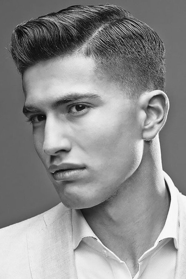 Black and white photo of young man with taper fade haircut with quiff