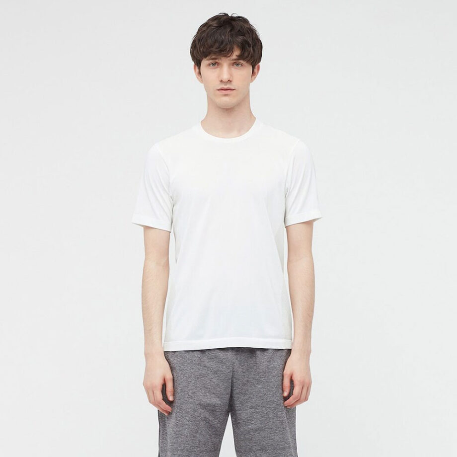 Dark haired man wearing a white Uniqlo t-shirt with grey pants