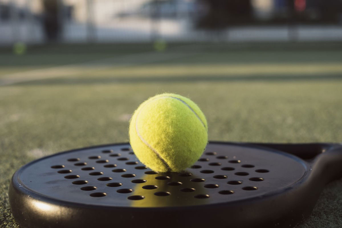 Close up image of a padel ball sitting onto of a padel racket.