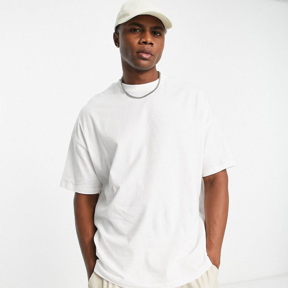Black man wearing an ASOS Design oversize white t-shirt and a white baseball cap.