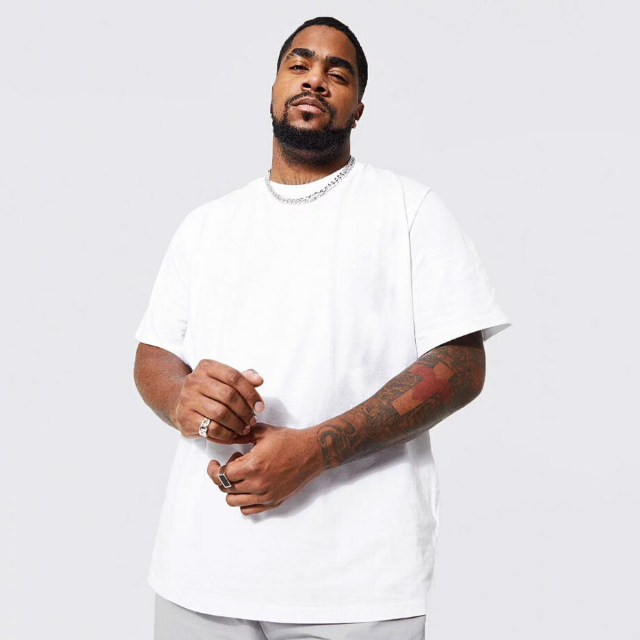 Black man with tattoos wearing a BoohooMan plus size white t-shirt