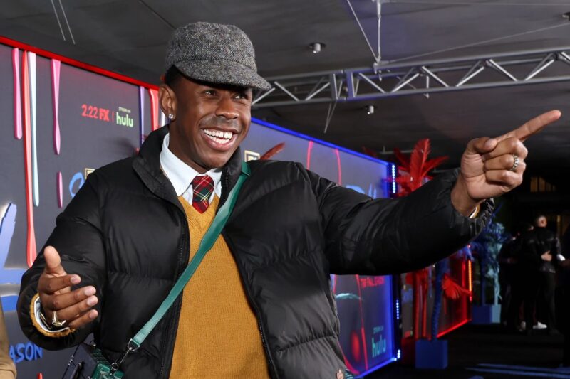 Tyler, the Creator smiles and points at a fan on the red carpet.