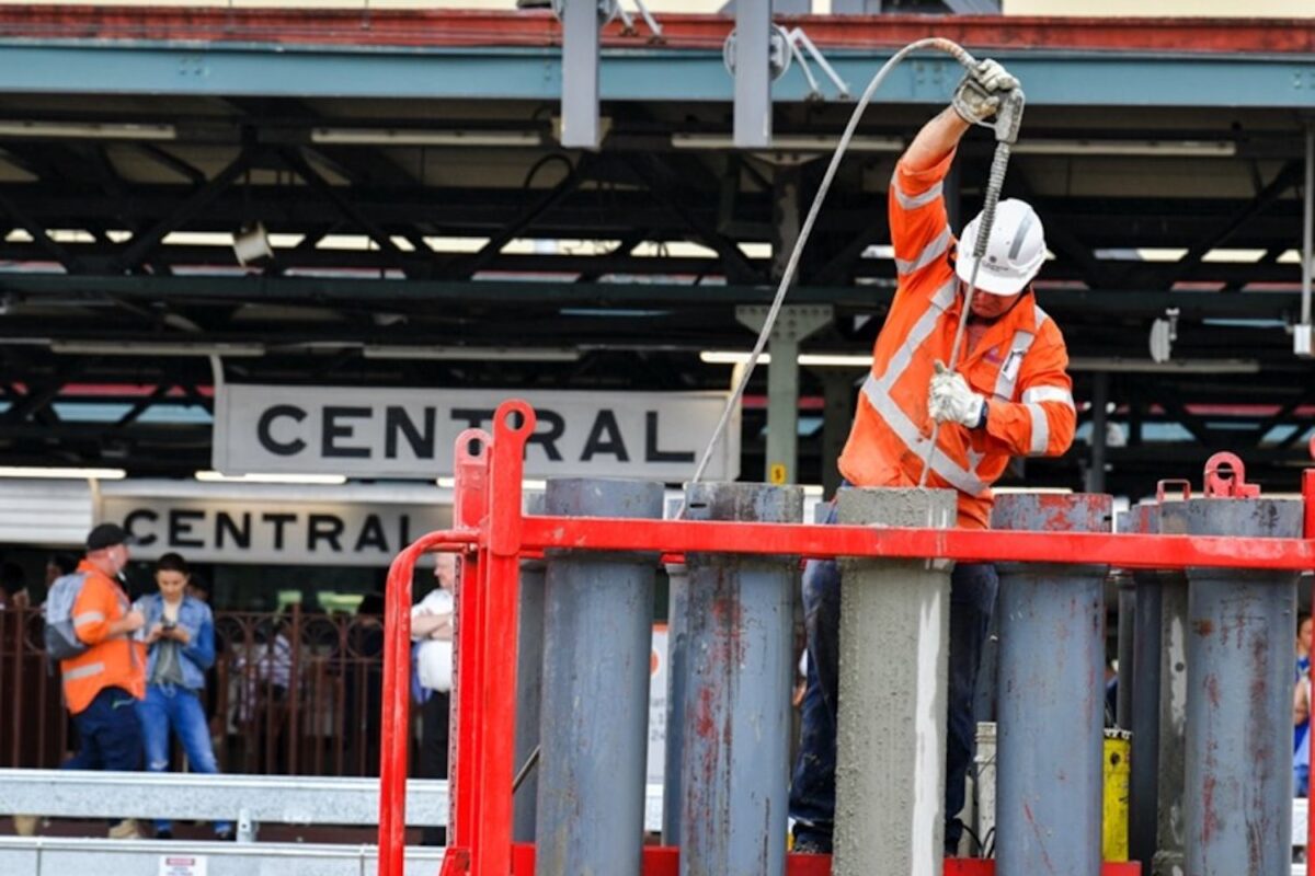 A construction worker wearing high-vis pours concrete at Central station in Sydney.