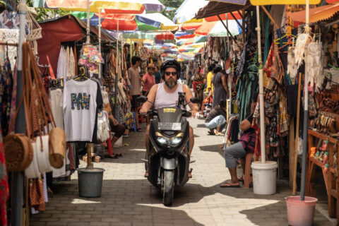 A foreign tourist riding a motorbike at the Ubud street art market in Bali.