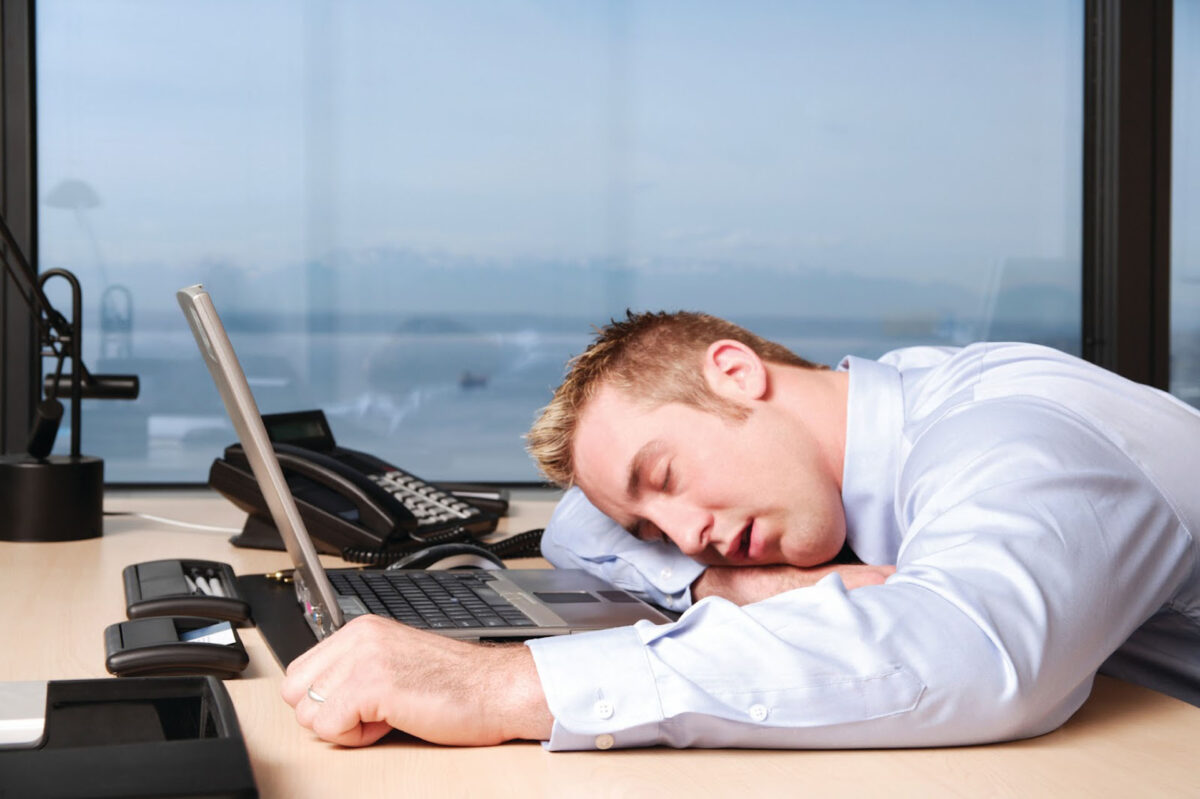 A man sleeping at his desk at work.
