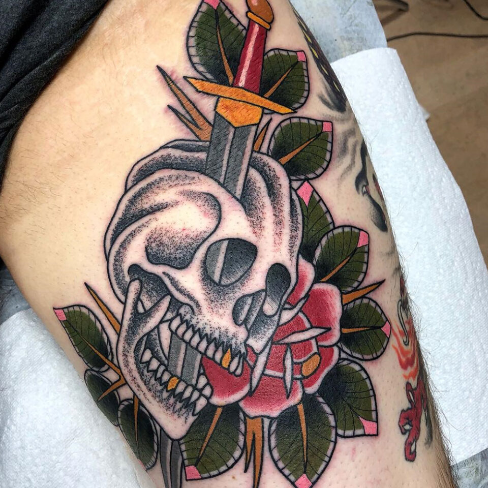 Sword piercing through skull with roses tattoo Source @mykechambers via Instagram