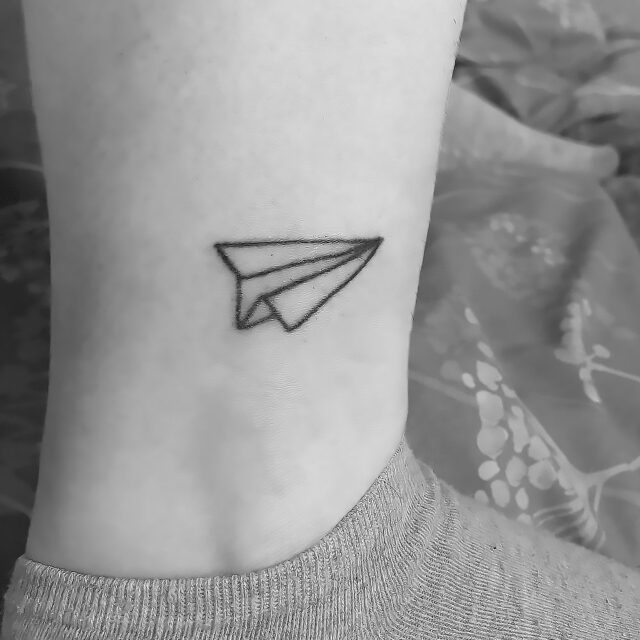 Fonte de tatuagem no tornozelo com contorno de avião @caitpokez via Instagram