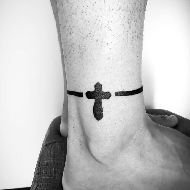 Fonte de tatuagem com cruz gótica no tornozelo @GeorgeWolfTattoo via Facebook