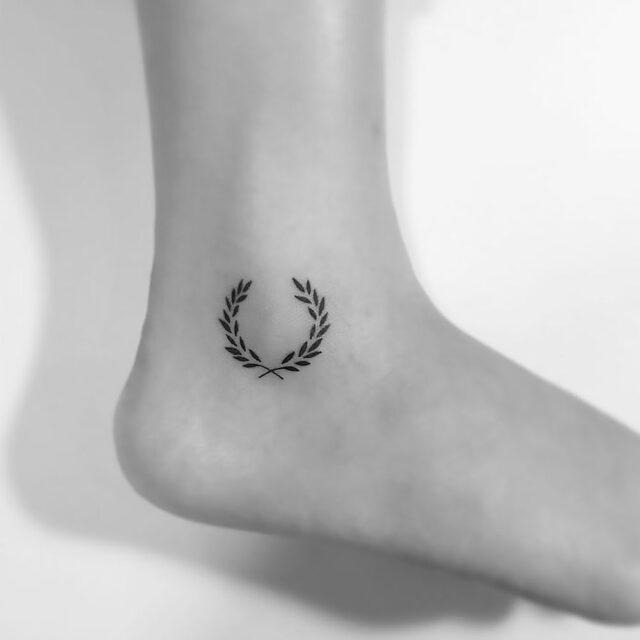 Fonte de tatuagem no tornozelo com coroa de louros grega @ playground_tat2 via Instagram