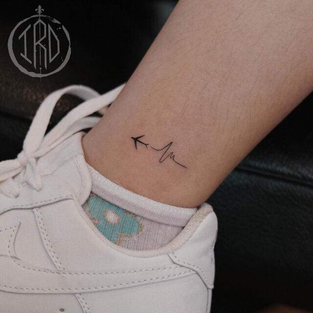 Fonte de tatuagem no tornozelo com batimento cardíaco @nhi.ink via Instagram