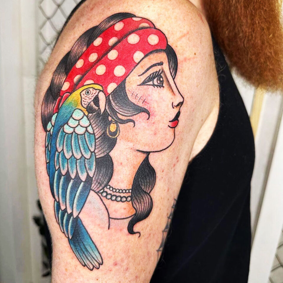 Fonte de tatuagem de animal de estimação de papagaio no ombro de um pirata @electricsnaketattoo via Instagram